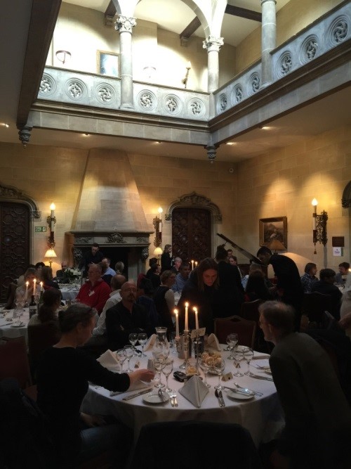 Groups of people sat at round tables in a decorative hall awaiting dinner