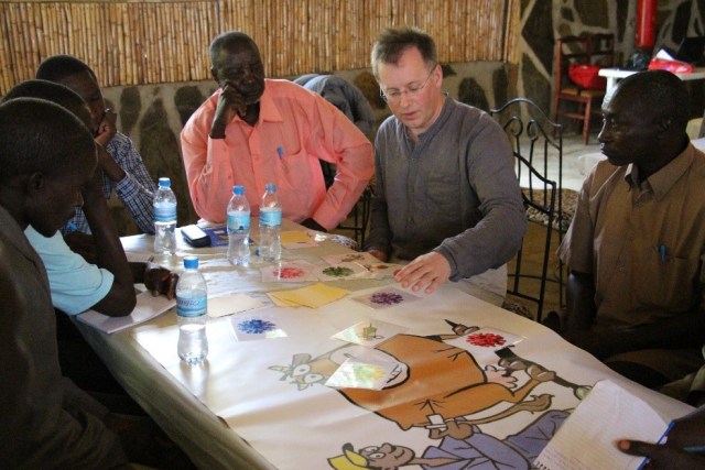 Five men sat around a table, listening to another man talk and explain the paperwork in front of them