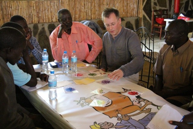 Five men sat around a table, listening to another man talk and explain the paperwork in front of them