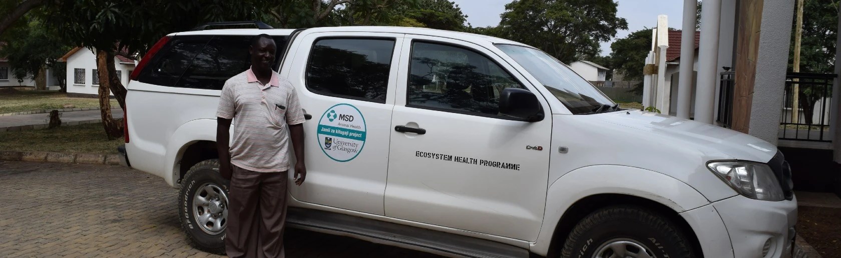 Man standing in front of a branded truck, in tree lined street