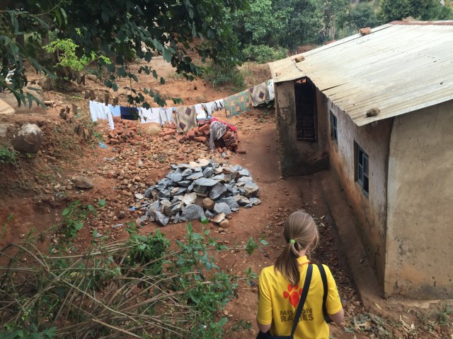 Woman wearing a Mission Rabies T-Shirt walks down a slope to a hill with a clothesline outside