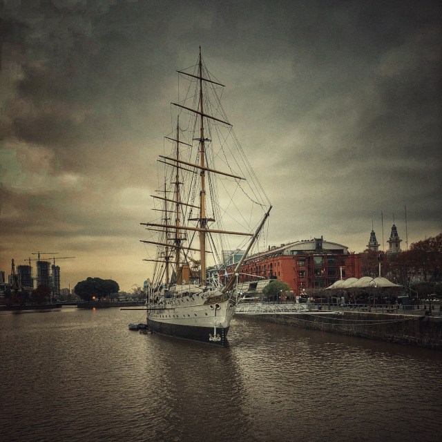 Tall Sailing Ship docked at a quayside, with city buildings in the background