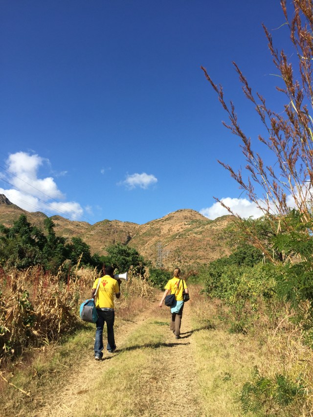 A man and a woman walking up a hill, both wearing Mission Rabies t-shirts