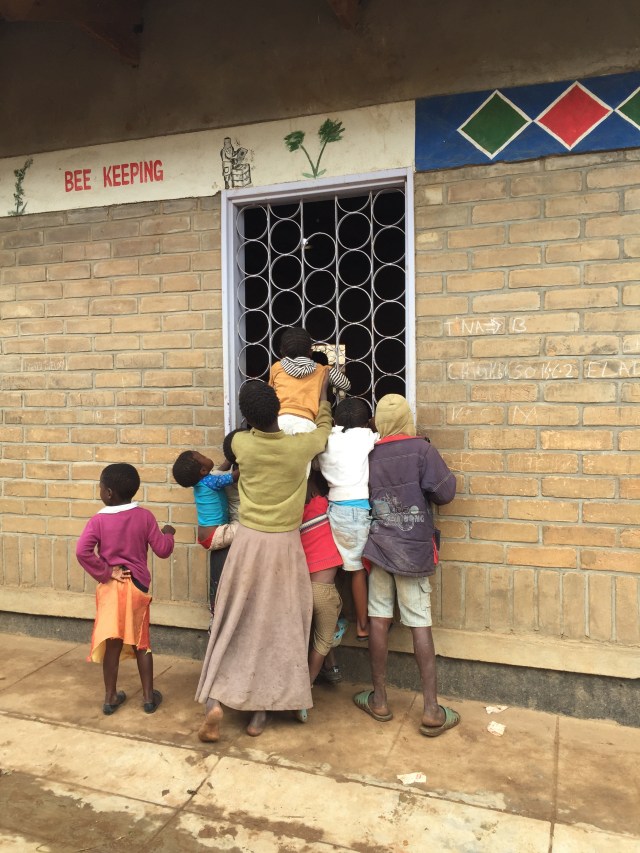 A group of children peer in a window of a brick building